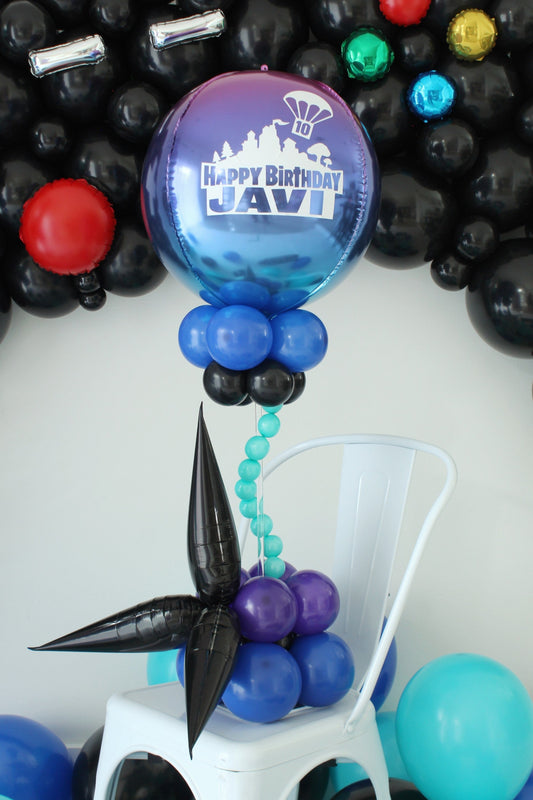 Gamer balloon centerpiece with a blue-purple ombré orb reading “Happy Birthday Javi,” aqua balloon bubbles, and black starburst accents.