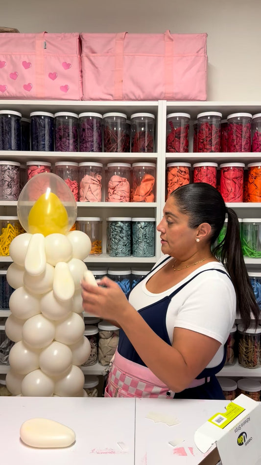 Woman creating an oversized white balloon candle with yellow flame during a Creative Heart Studio balloon tutorial.