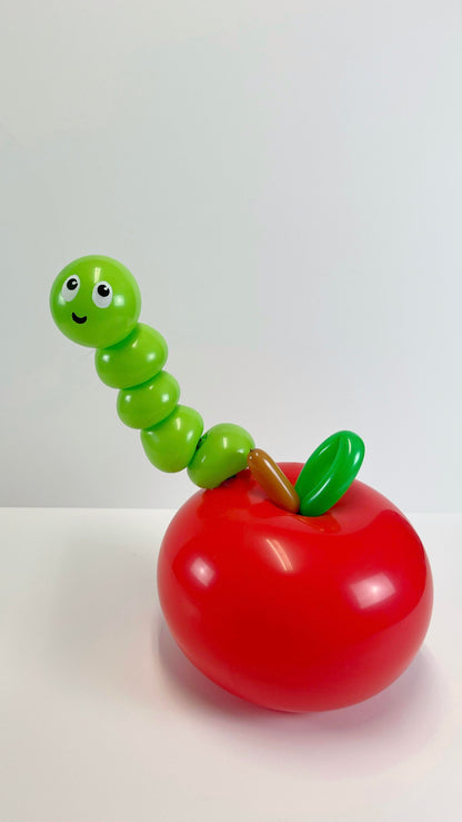 Adorable red apple balloon with a smiling green balloon worm peeking out, perfect for back-to-school balloon decorations, teacher appreciation gifts, and classroom centerpieces. This fun and whimsical design adds a playful touch to any school-themed event and is a great project for balloon artists looking to create cute and memorable balloon sculptures.