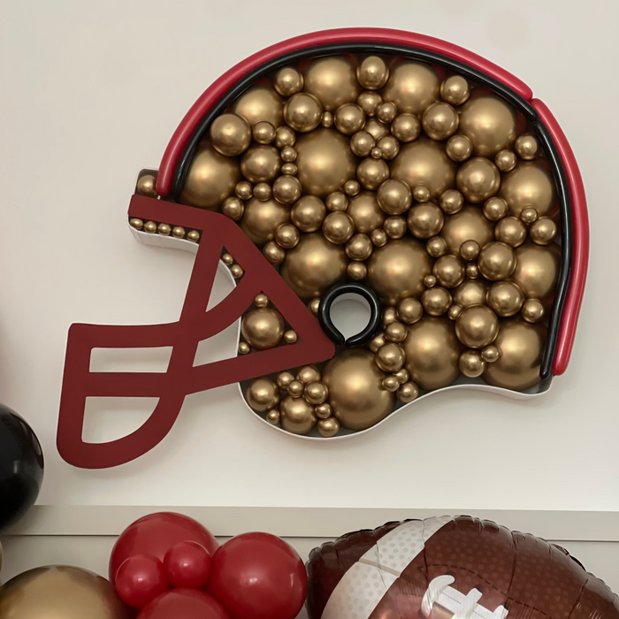 Decorative helmet with gold balls, red balloons, and a football on a white background