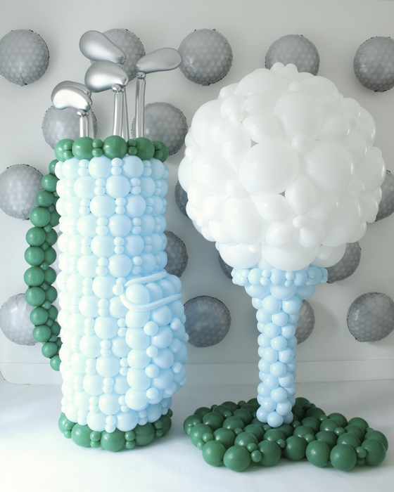 Creative balloon decor featuring a life-size golf bag with balloon clubs and a giant golf ball on a tee. Perfect for sports-themed balloon installations, golf tournaments, country club events, or athletic celebrations. This golf balloon design is an eye-catching option for decorators looking to wow clients with unique, sports-inspired balloon artistry.