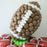 Oversized football balloon sculpture made with brown, white, and green balloons, perfect for sports-themed parties, football events, Super Bowl celebrations, and school spirit decor. Surrounded by foil football balloons, this creative balloon design makes a bold centerpiece for game day, tailgate setups, or athletic banquets.