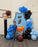 A young boy stands in front of a custom Basketball Jersey Backdrop featuring a light blue jersey with name and number, surrounded by black and blue balloon garlands, basketball hoops, and Wilson basketball props. Perfect for pep rallies, team banquets, and sports-themed parties, this backdrop captures the excitement of game day. Designed using the Basketball Jersey Backdrop Template from The Creative Heart Studio.