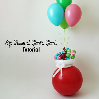 Whimsical Elf Arrival Santa Sack balloon decoration featuring a large red balloon base, tied with a white balloon bow and topped with an Elf on the Shelf, pastel presents, and floating helium balloons. This festive DIY project from Lilly Jimenez’s tutorial is perfect for Elf arrival ideas, holiday balloon décor, and creative Christmas setups.