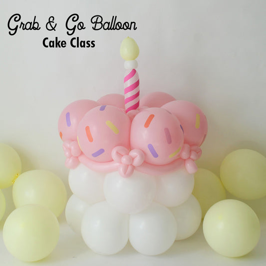 A cute balloon cake featuring pastel pink balloon “frosting” with colorful sprinkle cutouts, white balloon base, and a whimsical striped candle on top. Perfect for party deliveries, grab & go setups, or birthday-themed balloon decor. Learn how to make this easy and festive design in the Grab & Go Balloon Cake Tutorial—includes downloadable SVG sprinkle file for Cricut or Silhouette users.