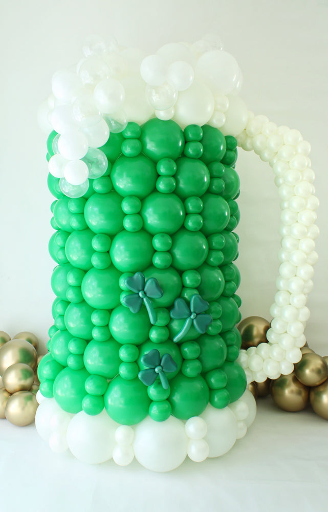 St. Patrick’s Day Green Beer Mug Balloon Decoration
Title: Large Beer Mug Balloon Sculpture – St. Patrick’s Day Balloon Class
Description: This oversized green beer mug balloon sculpture is the perfect centerpiece for St. Patrick’s Day celebrations! Designed with vibrant green balloons, frothy white balloon foam, and shamrock accents, this festive piece adds a fun and playful touch to any party or event. Learn to create this bubbly masterpiece in Lilly Jimenez’s St. Patrick’s Day Balloon Class.