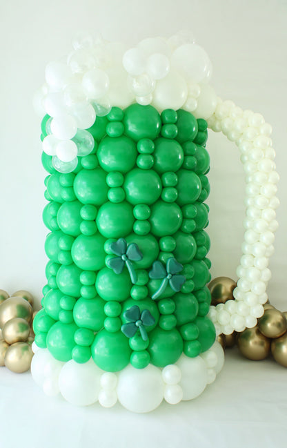 St. Patrick’s Day Green Beer Mug Balloon Decoration
Title: Large Beer Mug Balloon Sculpture – St. Patrick’s Day Balloon Class
Description: This oversized green beer mug balloon sculpture is the perfect centerpiece for St. Patrick’s Day celebrations! Designed with vibrant green balloons, frothy white balloon foam, and shamrock accents, this festive piece adds a fun and playful touch to any party or event. Learn to create this bubbly masterpiece in Lilly Jimenez’s St. Patrick’s Day Balloon Class.