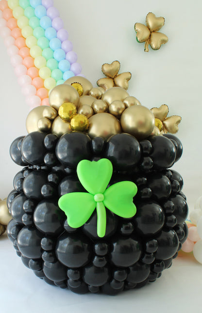 St. Patrick’s Day Pot of Gold Balloon Decoration
Title: Large Pot of Gold Balloon Sculpture – St. Patrick’s Day Balloon Class
Description: Bring the luck of the Irish to your celebrations with this Pot of Gold balloon sculpture! Designed with glossy black balloons, shimmering gold balloon coins, and a pastel rainbow backdrop, this stunning creation is a perfect St. Patrick’s Day statement piece. Learn to make this magical design in Lilly Jimenez’s balloon class.