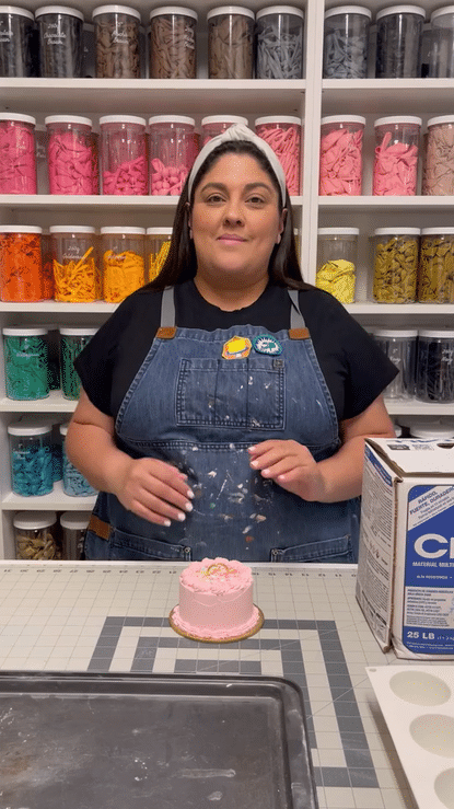 Lilly Jimenez smiles while teaching her Balloon Weights Class, showing how to make a pink cake-inspired balloon weight using an easy-to-find, budget-friendly item. Surrounded by jars of balloons, she shares her creative tips for crafting stylish, functional balloon anchors that look sweet enough to be dessert—but don’t eat them! Perfect for adding charm and personality to your party setups.
