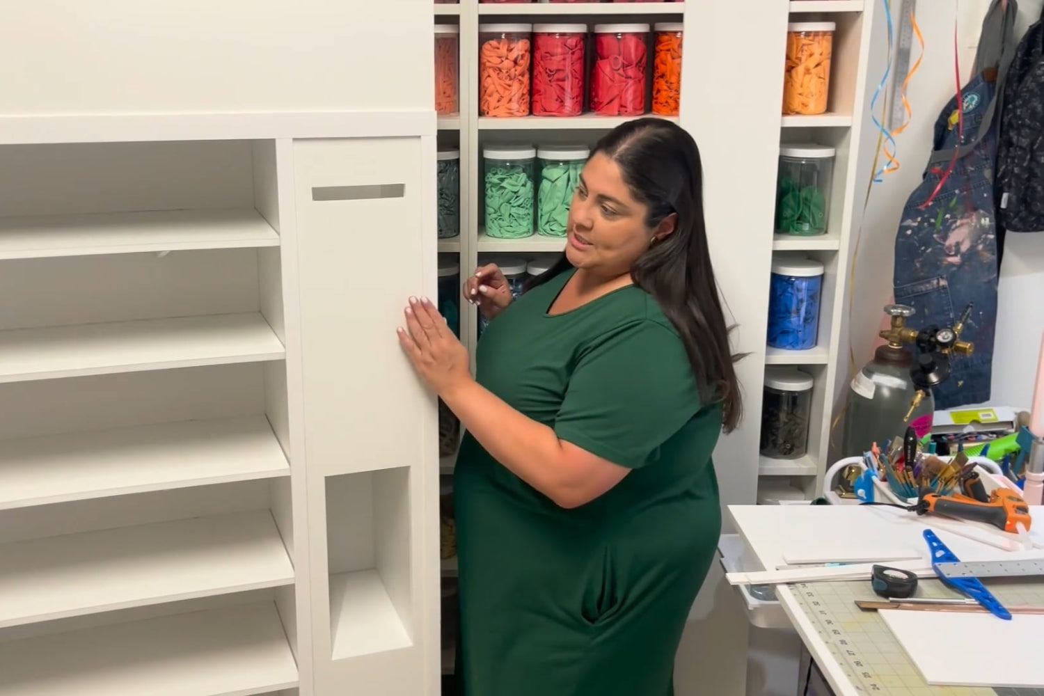 Lilly Jimenez of Creative Heart Studio demonstrates how to build a foamboard vending machine during her step-by-step tutorial. She’s seen assembling the prop in her craft studio, surrounded by color-coded balloon jars and professional tools. This behind-the-scenes look highlights the hands-on, creative approach of her Foamboard Vending Machine Class—perfect for balloon artists, event decorators, and DIY party pros.