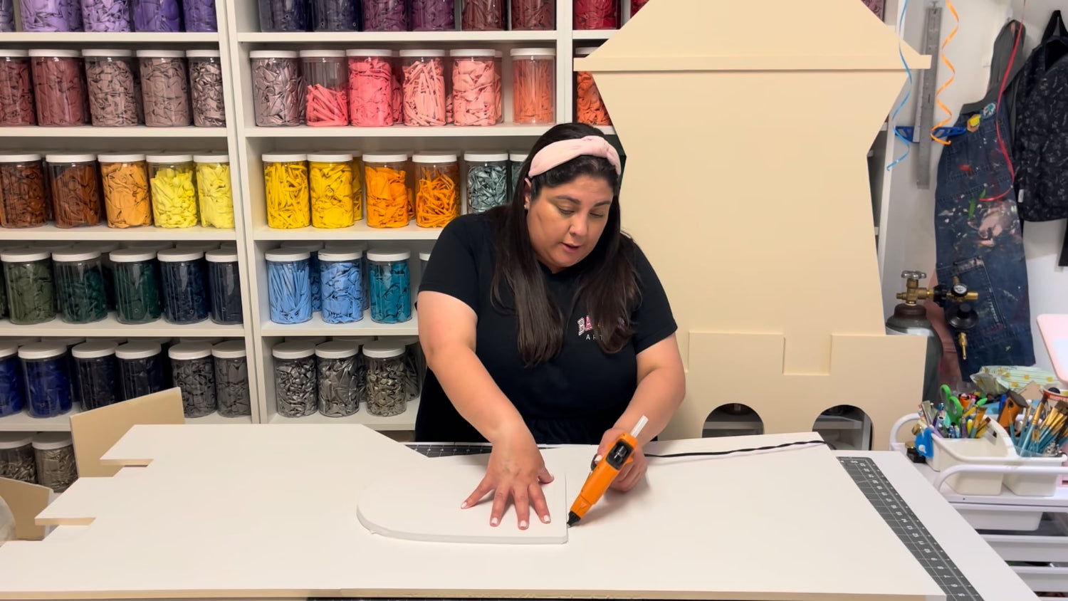 Lilly Jimenez uses her favorite Gorilla Glue Gun to assemble 1/2" foam board pieces for the Sand Castle Backdrop in her creative studio. With walls of colorful balloon jars in the background, she walks students through the hands-on building process featured in her DIY backdrop class from The Creative Heart Studio.