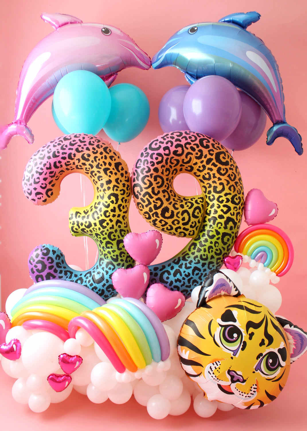 A vibrant, Lisa Frank-inspired balloon arrangement that’s a ‘90s girl’s dream! Featuring large leopard-print foil number balloons "39," playful pink and blue dolphin foil balloons, pastel latex balloons, and a bold tiger face foil balloon. The display is completed with rainbow balloon arches, pink heart-shaped balloons, and a fluffy white balloon base, all set against a soft pink backdrop. This colorful and nostalgic setup brings back the iconic, bold, and whimsical style of the ‘90s.