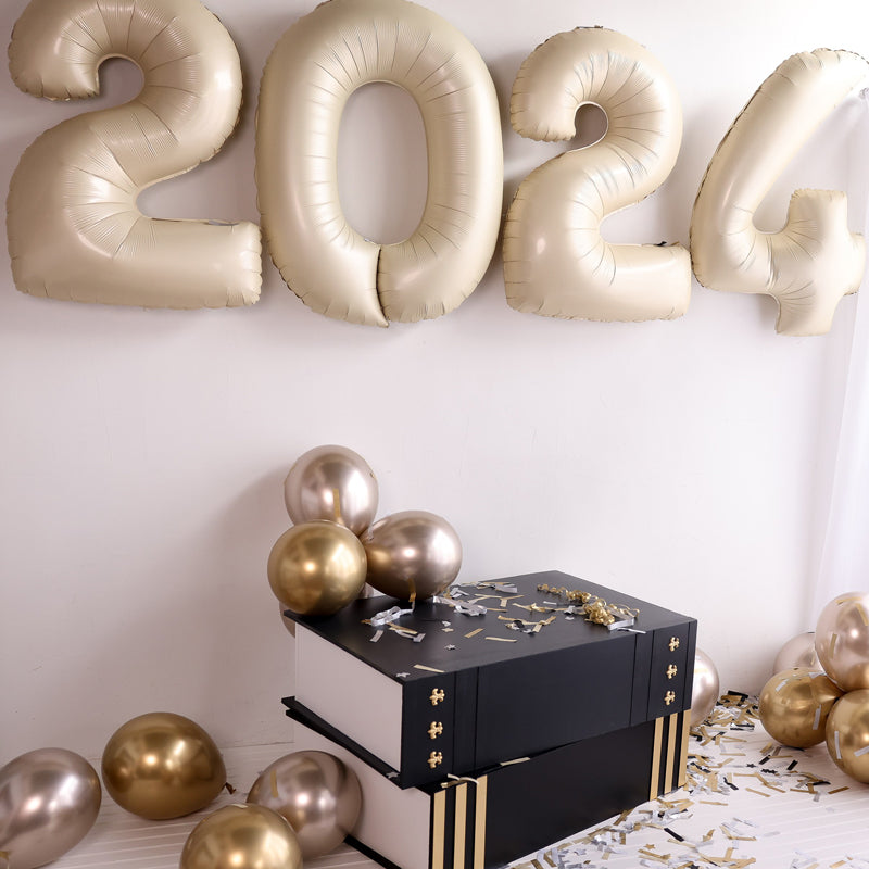 A black and gold oversized book prop sits beneath large gold 2024 balloons, surrounded by gold and champagne balloons and scattered confetti. This elegant setup is perfect for graduation photoshoots, event decor, and literary-themed celebrations. Designed by Lilly Jimenez of The Creative Heart Studio, this prop adds a stylish touch to milestone events. Part of the Oversized Book Prop Class!