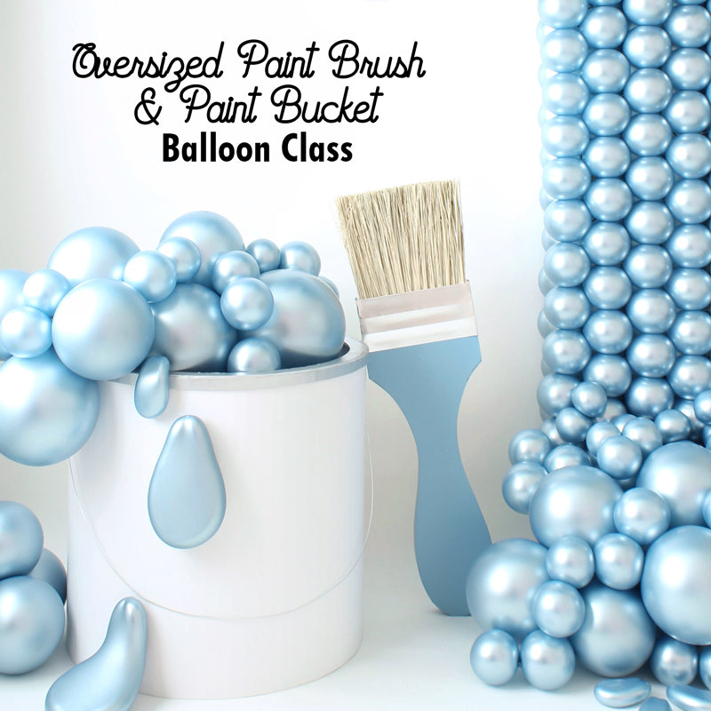 A white oversized paint bucket prop overflowing with metallic blue balloon "paint", paired with a matching oversized paintbrush prop and a cascading balloon paint effect in the background. This creative and whimsical setup is part of Lilly Jimenez’s Oversized Paint Brush & Paint Bucket Balloon Class at The Creative Heart Studio. Perfect for art-themed events, photoshoot backdrops, and creative decor setups.