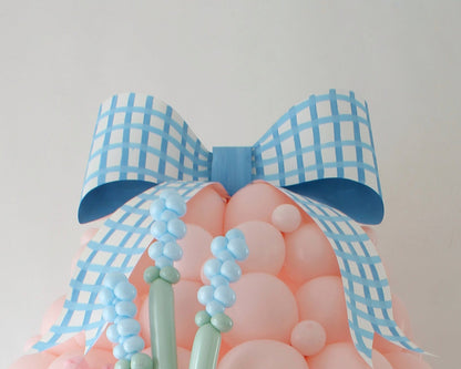 Oversized blue gingham paper bow attached to the top of a pastel pink balloon egg, perfect for decorating Easter balloon displays, Mother’s Day backdrops, or spring-themed events. The bow measures approximately 36" wide by 27" tall and adds a whimsical touch to large party decorations. Printable paper bow template for party decorations.