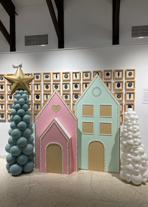 Oversized pastel gingerbread houses in pink and mint green with candy-style trim, paired with balloon Christmas trees, including one topped with a gold star. A creative Christmas display perfect for holiday photo ops, parties, and festive event decor.
