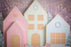 Oversized pastel gingerbread village backdrop featuring pink, mint green, and light blue foam board houses adorned with candy-style trim, pearl wreaths, and glowing string lights—perfect for Christmas photo shoots, kids’ holiday parties, or festive winter decor displays.