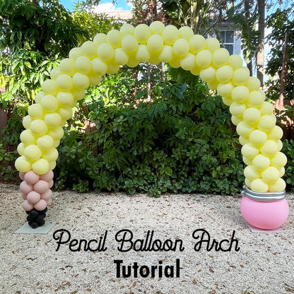 Colorful pencil-shaped balloon arch with yellow, pink, black, and silver balloons, set outdoors in front of greenery. Perfect for school events, back-to-school photo ops, or teacher appreciation setups. This arch was created for the Pencil Balloon Arch Tutorial, which teaches how to build this fun and festive decor piece step-by-step.