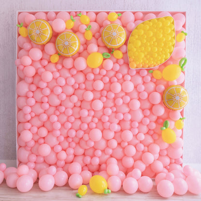 A playful pink balloon mosaic wall featuring a vibrant lemon theme. Yellow balloon lemons and citrus slice accents pop against the pink background, with a large half-lemon mosaic design in the top corner. This juicy summer-inspired balloon wall is perfect for parties, photo ops, or citrus-themed events and is part of Lilly Jimenez’s Balloon Mosaic® Walls Course.