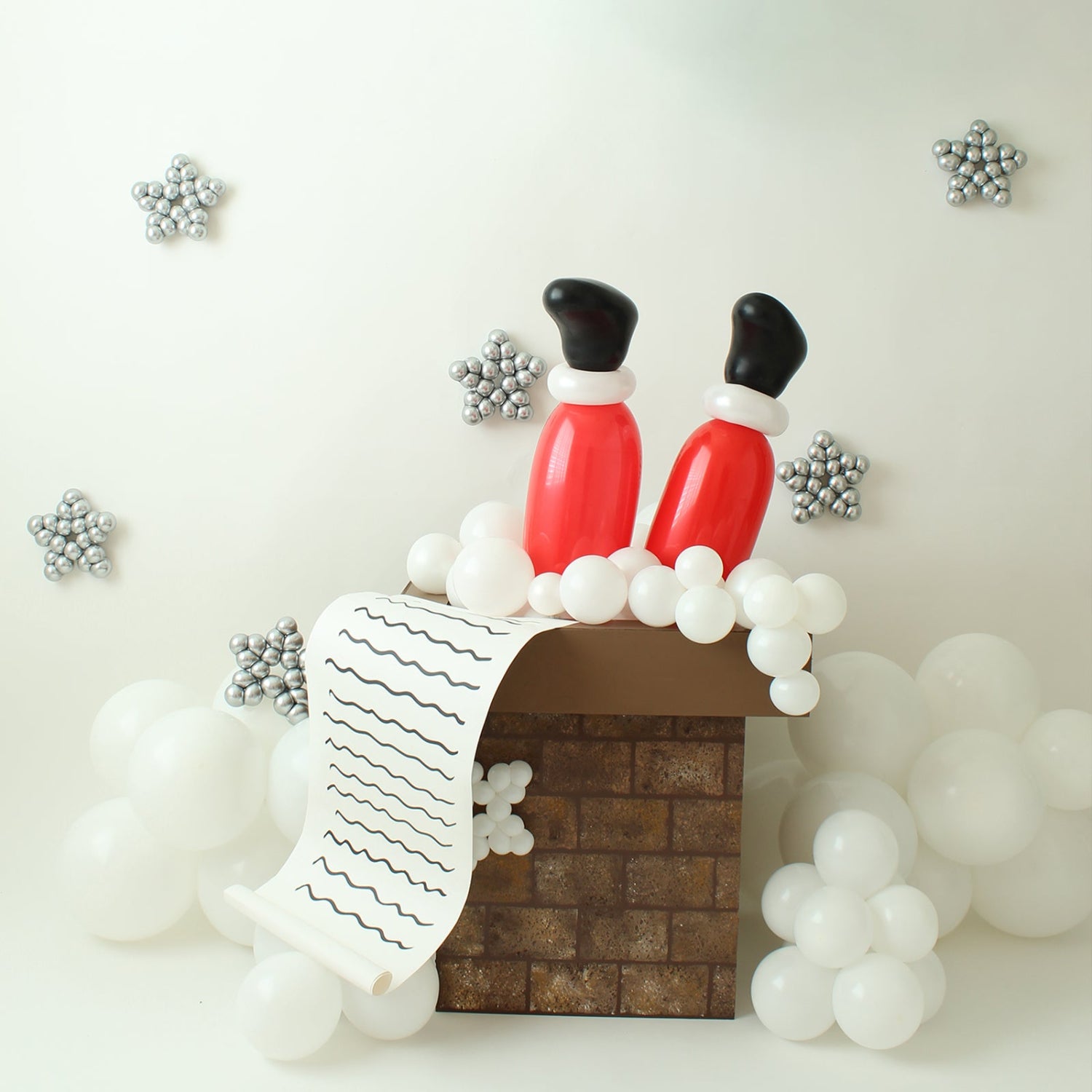 Whimsical Santa Chimney balloon display featuring red balloon legs, white balloon snow, and a foam board chimney painted with a brick pattern. Perfect for Christmas parties, holiday photo ops, and festive event décor.