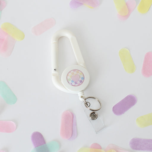 white carabiner with cute pink balloon on a rainbow checkered background