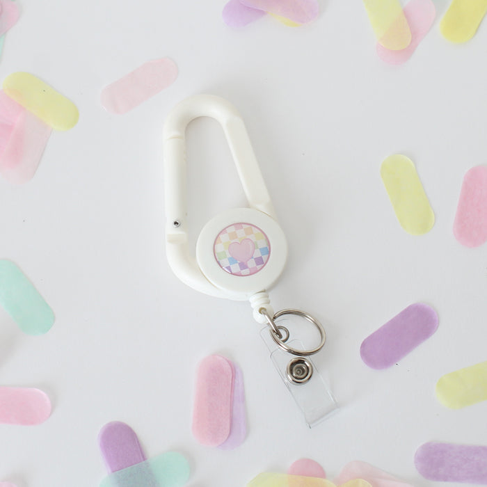white carabiner with cute pink balloon on a rainbow checkered background