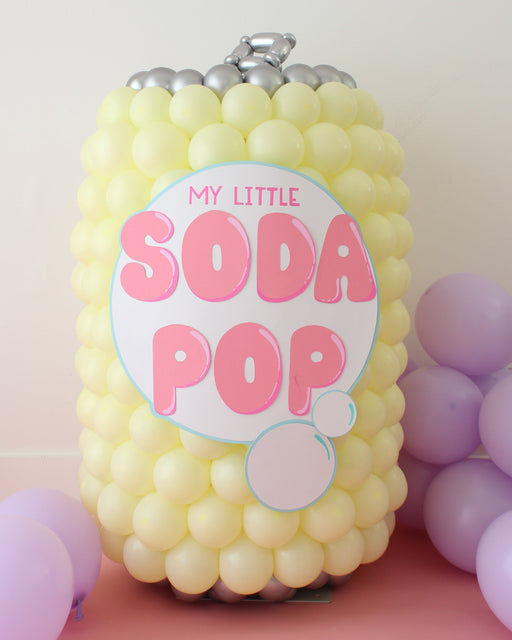 A pastel yellow balloon sculpture shaped like a soda can with silver balloons on top and a pink-and-white label that reads “My Little Soda Pop.” This oversized balloon prop is perfect for birthday parties, K-Pop or Demon Hunters themes, and fun photo backdrops. Ideal for balloon artists or DIY decorators creating colorful event décor, soda can balloon centerpieces, or playful pop-inspired displays.