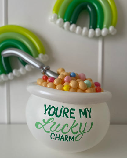 White balloon cereal bowl filled with pastel balloon “cereal” and a silver spoon, with green monochrome rainbow balloons in the background. Features “You’re My Lucky Charm” text on the bowl. This festive balloon display is taught in Lilly Jimenez’s You’re My Lucky Charm Balloon Class—perfect for St. Patrick’s Day decor, parties, or themed photoshoots.