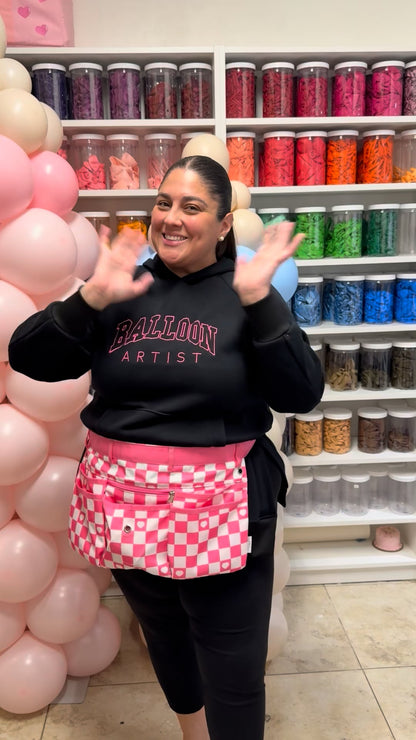 Lilly Jimenez wearing the Creative Heart Studio balloon artist apron and Balloon Artist hoodie inside the studio. This behind-the-scenes moment highlights functional balloon art apparel designed for professional balloon decorators, event stylists, and creatives who want comfort, durability, and style while building balloon installations.