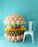 Large balloon burger sculpture next to white chair showing scale on blue background