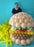 Lilly standing behind large balloon burger sculpture showing scale on blue background