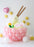 Balloon ramen bowl centerpiece with pink balloon base, spiral noodles, egg, fish cake, and floating chopsticks on white background