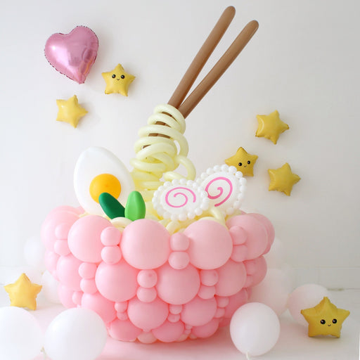 Kawaii balloon ramen bowl with pink balloon base, spiral noodles, egg, fish cake, and floating chopsticks centerpiece
