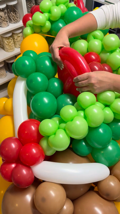 Close up of balloon taco showing lettuce, tomato, and filling details being placed by hand