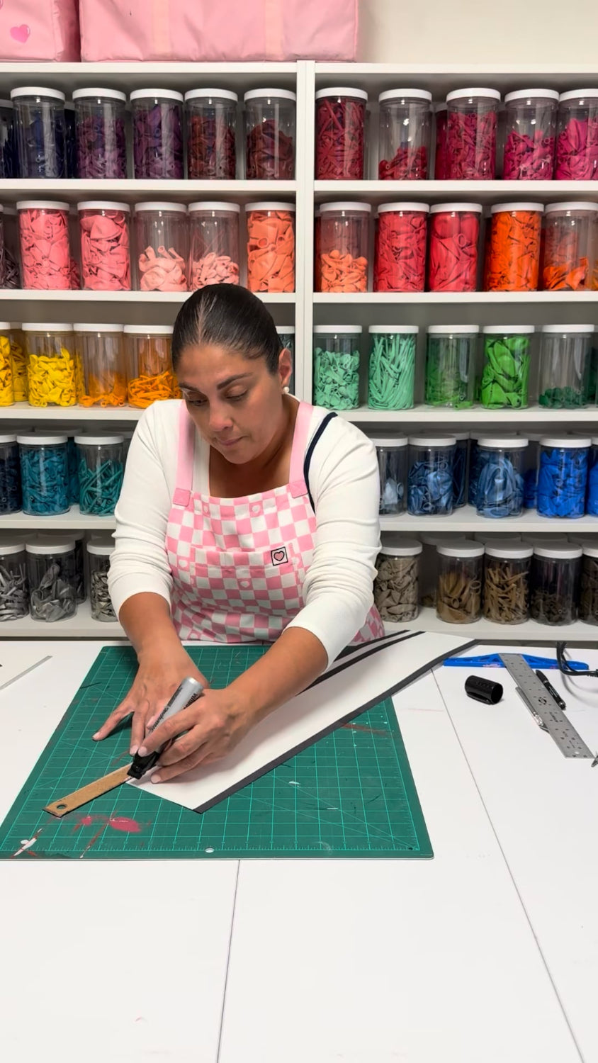 Lilly cutting black foam board for an oversized film reel prop in the Cinema Party Decor Class, teaching movie night decorations, Hollywood themed props, theater party displays, and DIY cinema party decor.
