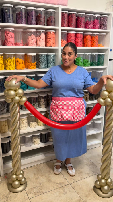 Lilly standing with red carpet balloon stanchions made from gold balloon columns and a red balloon rope for the Cinema Party Decor Class, movie night entrances, Hollywood themed parties, VIP areas, and photo op displays.