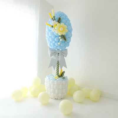 Easter egg balloon column topiary with basket base, balloon flowers, and oversized bow for spring decor and Easter party setup