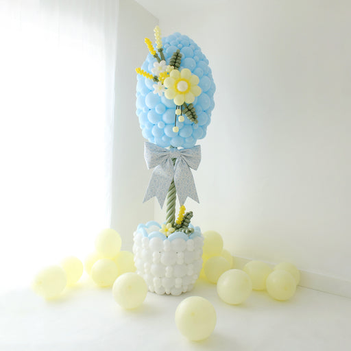 Easter egg balloon column topiary with basket base, balloon flowers, and oversized bow for spring decor and Easter party setup