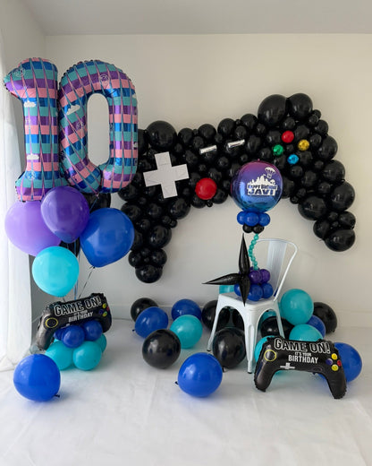 Gamer birthday display with a black controller balloon sculpture, number 10 balloons, and a personalized “Happy Birthday Javi” orb centerpiece.
