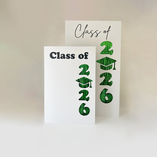 Class of 2026 graduation backdrop templates with bold cut-out numbers and graduation cap design backed with green foil fringe, displayed as layered backdrop panels, perfect for DIY graduation party decor, balloon backdrop styling, photo booth setups, and event decorators creating graduation installations