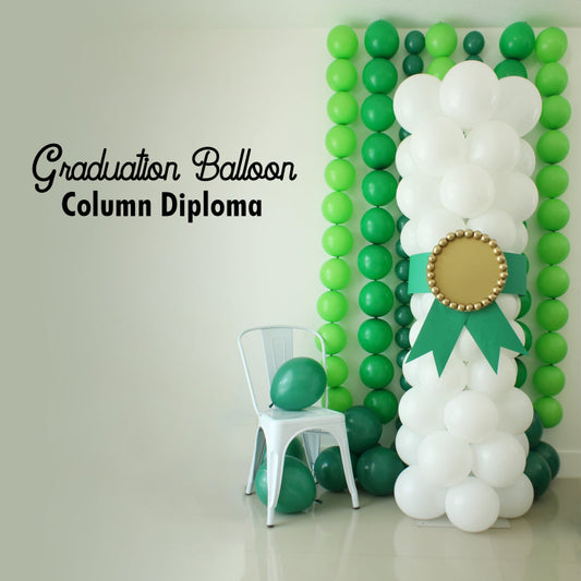 Graduation Balloon Column Diploma made from stacked white balloons with a green ribbon and gold medallion detail, styled in front of a green balloon garland wall. Ideal for photo backdrops or stage decor at graduation parties for any grade level.
