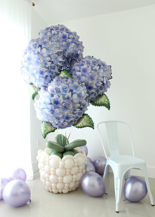 Large linking balloon flower pot topped with blue hydrangea foil balloons and green balloon leaves for a floral balloon bouquet display.