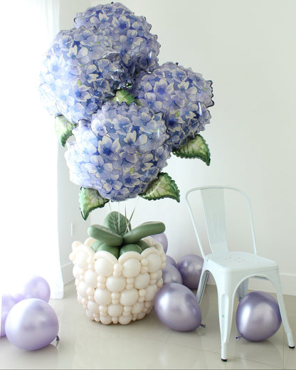 Oversized blue hydrangea foil balloons arranged in a white linking balloon flower pot with green balloon leaves.