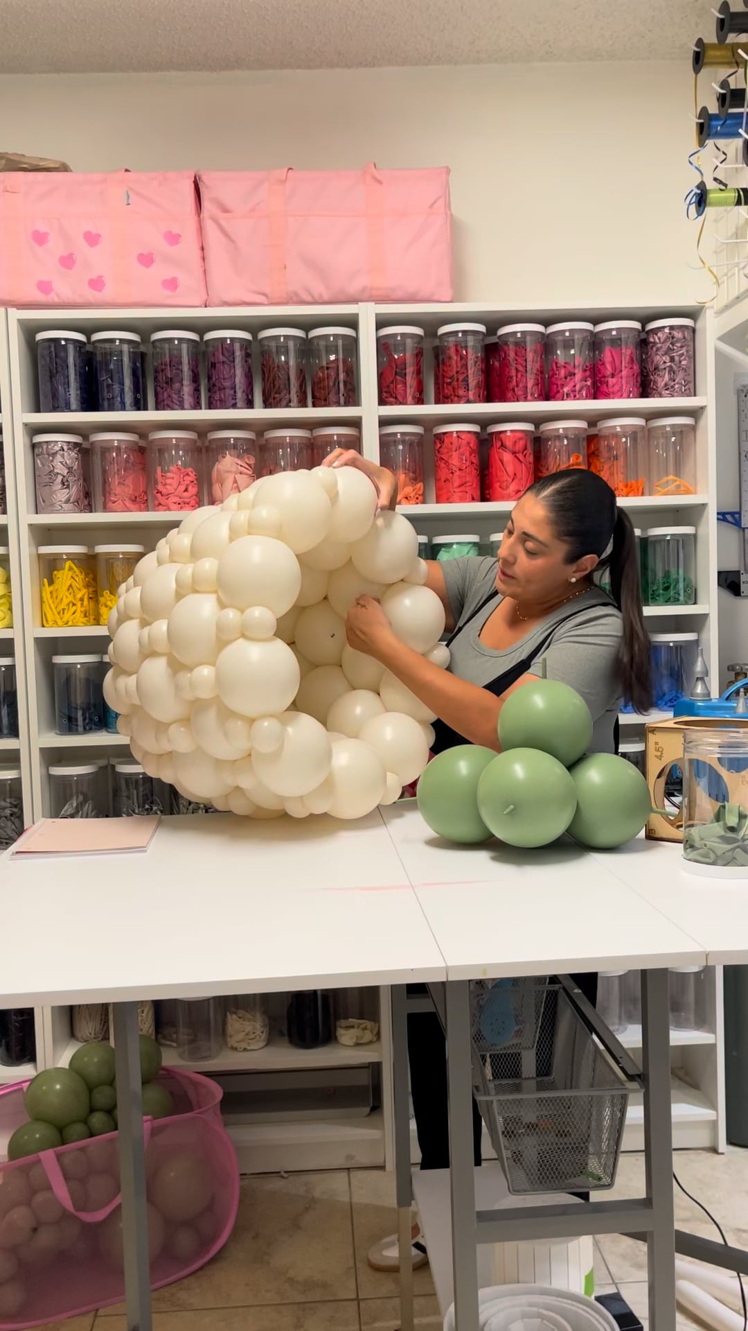Balloon artist, Lilly Jimenez, building a white linking balloon flower pot during a step-by-step balloon decor tutorial.