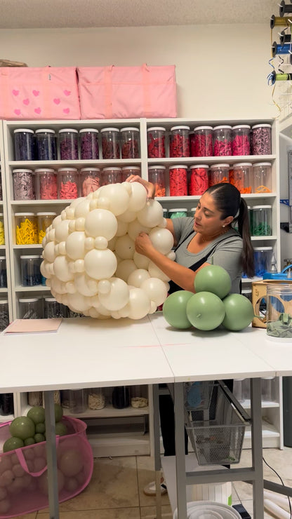 Balloon artist, Lilly Jimenez, building a white linking balloon flower pot during a step-by-step balloon decor tutorial.