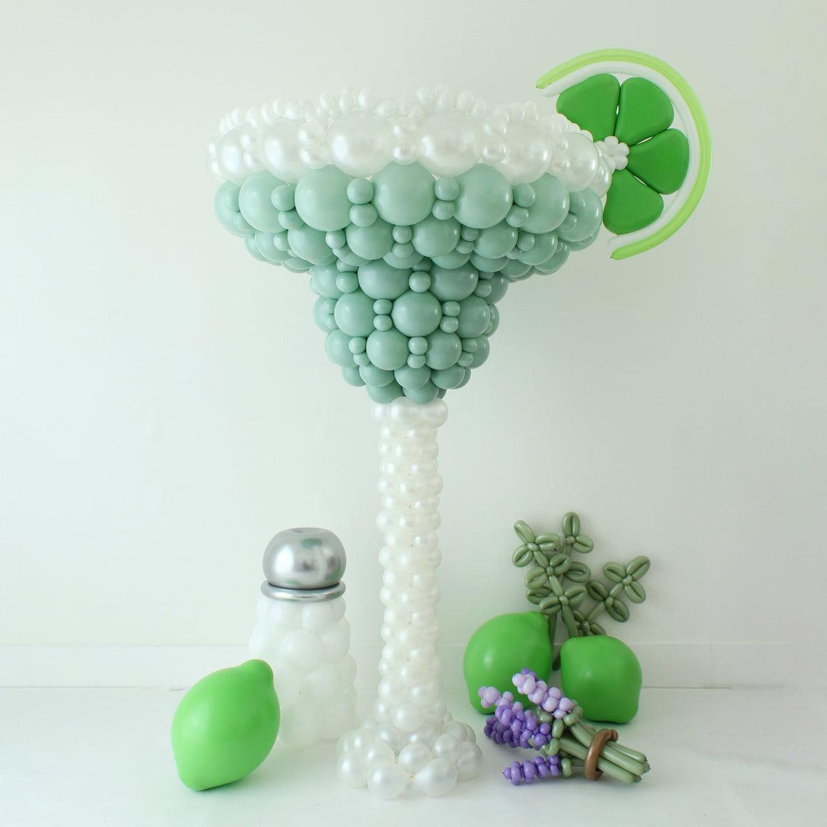 Oversized mint green Margarita Glass Balloon Sculpture with balloon lime wedge, salt shaker, limes, and lavender accents