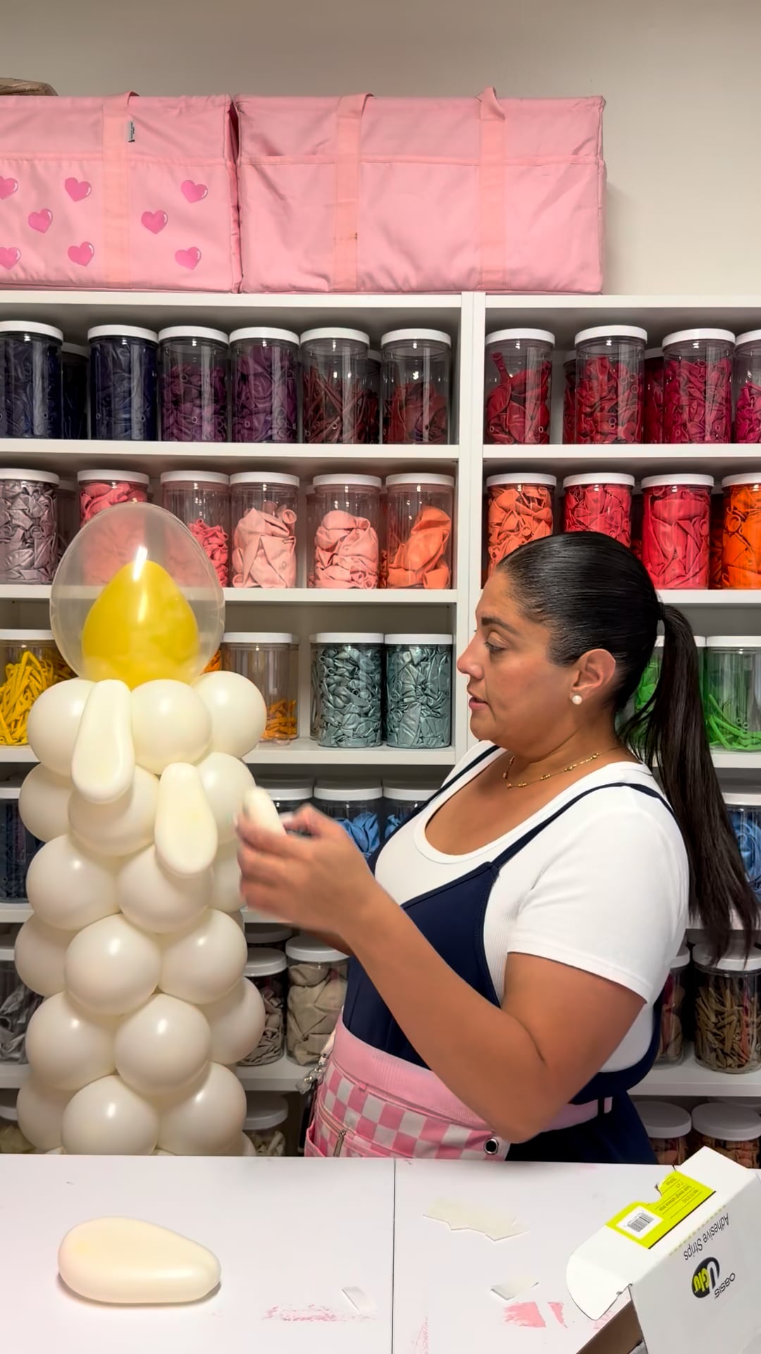 Woman creating an oversized white balloon candle with yellow flame during a Creative Heart Studio balloon tutorial.