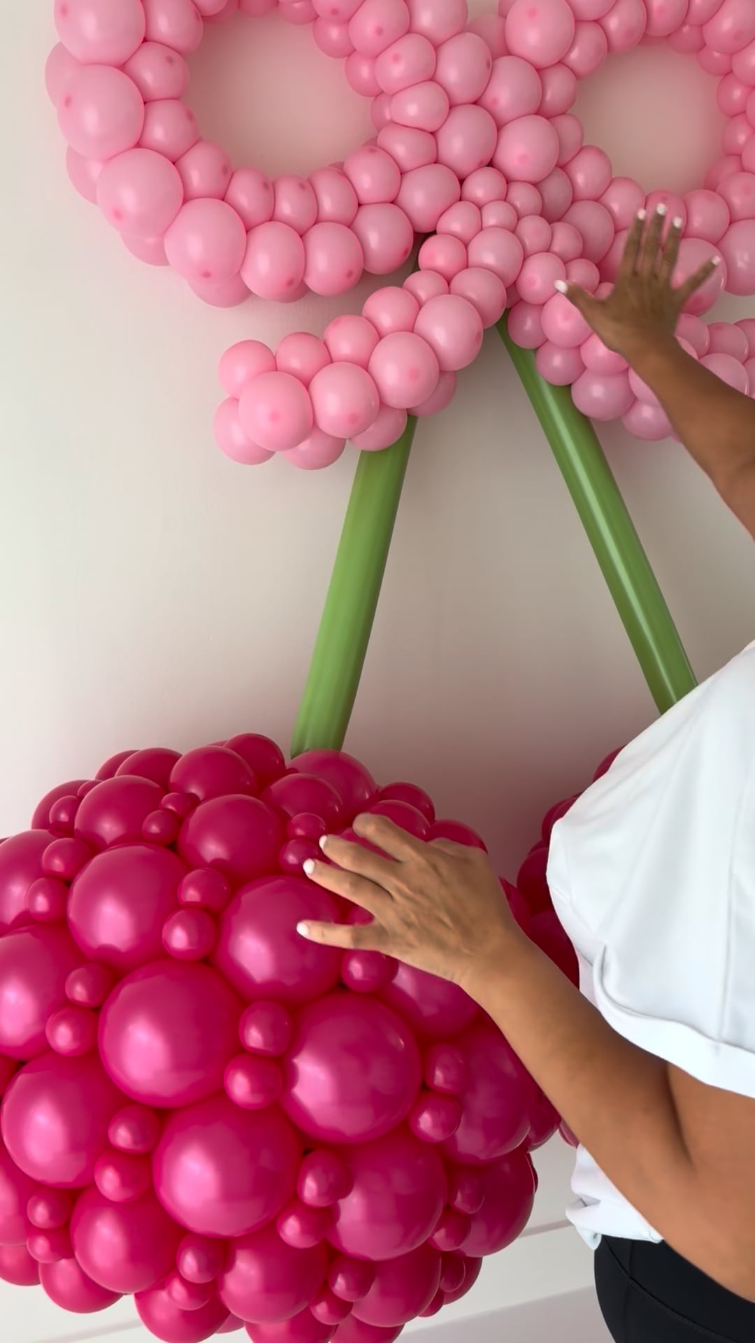 Close-up of an oversized balloon cherry and pink balloon bow during construction in the balloon tutorial.