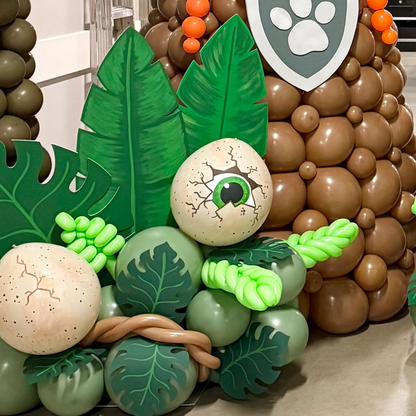 Painted dinosaur egg balloons with cracked-eye and speckled designs displayed in a jungle-themed balloon installation.
