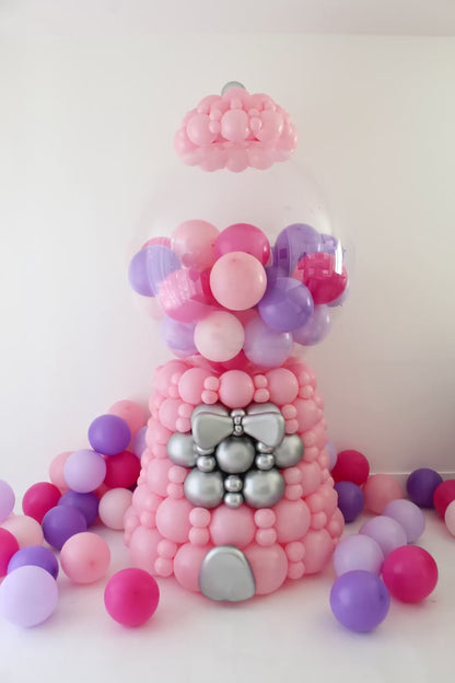 Animated view of an oversized linking balloon gumball machine decor featuring a pink balloon base, silver accent details, and a clear bobo globe filled with pink and purple mini balloons. The animation highlights the rotating gumball machine handle and front details, showing the scale and finished look of this 7 to 7.5 foot tall freestanding balloon design for birthday parties, candy themed events, storefront displays, photo backdrops, and large scale balloon installs.